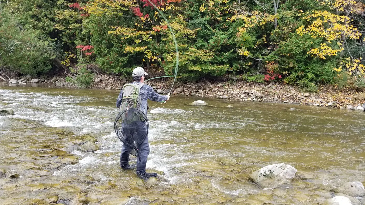 An angler fly fishing a riffle on the Bighead River in fall